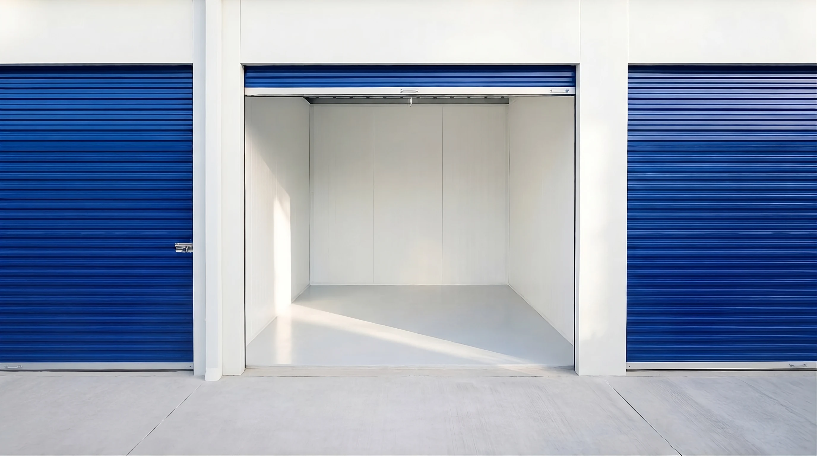 Una bodega vacía y limpia con su puerta azul abierta, entre dos bodegas cerradas.